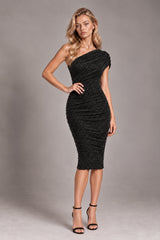 A woman modeling a black one-shoulder bodycon midi dress with a textured, ruched finish, paired with black strappy high-heeled sandals, against a neutral gray studio background.