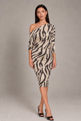 A woman models a one-shoulder bodycon dress with a beige and black zebra print pattern, paired with black high-heeled sandals, against a neutral gray studio background.