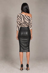 A woman shown from the back wearing a beige and black zebra-print off-the-shoulder top and a black faux-leather pencil skirt, paired with black high heels, against a neutral gray studio background.