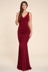 Woman wearing a burgundy berry evening gown on a beige background