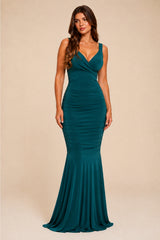 Woman wearing a teal green evening maxi gown against a beige background
