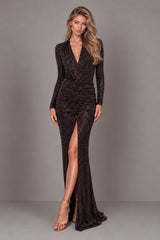 A woman modeling a long-sleeve, deep V-neck bodysuit with a sequin maxi floor-length skirt covered in shimmering brown sequins, featuring a high front slit and a slight train, set against a solid grey studio background.