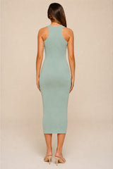 A woman viewed from the back wearing a sleeveless, bodycon midi dress in a pale sage green color, paired with beige high-heeled sandals, against a solid beige studio background.