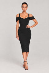 A woman modeling a black off-the-shoulder bodycon midi dress with structured short sleeves and a sweetheart neckline, paired with black strappy high-heeled sandals, against a light gray studio background.