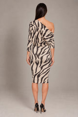 A woman viewed from the back wearing a one-shoulder bodycon midi dress with a bold black and beige zebra print, paired with black high heels, against a neutral gray studio background.