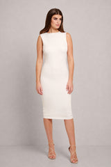 A woman modeling a sleeveless, bodycon midi dress in off-white, paired with nude lace-up high heels, against a neutral gray studio background.