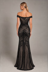 A woman modeling an off-the-shoulder black lace and mesh mermaid gown, shown from the back against a neutral gray studio background.