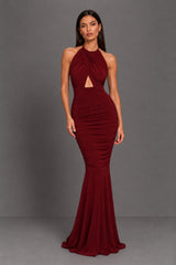 Woman wearing a burgundy berry evening gown on a grey background