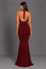 Woman wearing a burgundy berry evening gown on a grey background