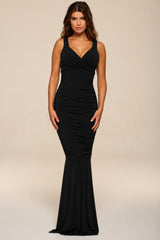 Woman wearing a black evening maxi gown against a beige background