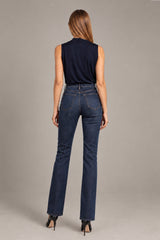 A woman shown from the back wearing dark blue high-waisted straight-leg jeans, a sleeveless navy top, and black heels against a solid gray studio background.