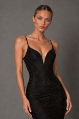 A woman modeling a fitted black spaghetti-strap evening dress covered in sparkling rhinestones against a solid gray studio background.