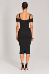 A woman viewed from the back wearing a fitted black cold-shoulder midi dress with shoulder cutouts and black high-heeled sandals against a light gray studio background.